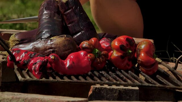 A rustic outdoor scene of vegetables grilling over a wood fire, an essential step in making traditional Romanian zacusca. The fire-roasted vegetables bring out deep, smoky flavors