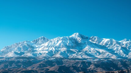 A mountain range covered in snow against a bright blue sky.