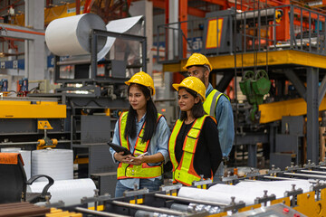 Three civil engineers from different cultures and ethnicities put their expertise together using technology and digital device to support a metal sheet production in a factory. Inclusive design