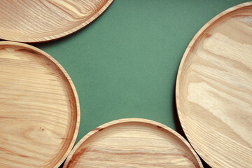 Wooden flat plates on a green background. The concept of ecological tableware. Products for modern kitchen. Zero emissions.