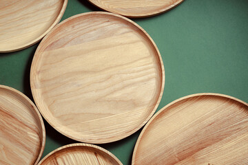 Wooden flat plates on a green background. The concept of ecological tableware. Products for modern kitchen. Zero emissions.