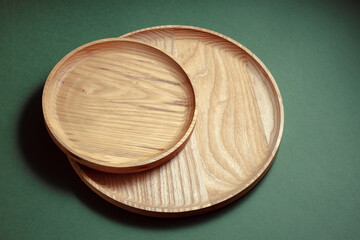 Wooden flat plates on a green background. The concept of ecological tableware. Products for modern kitchen. Zero emissions.