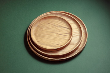 Wooden flat plates on a green background. The concept of ecological tableware. Products for modern kitchen. Zero emissions.