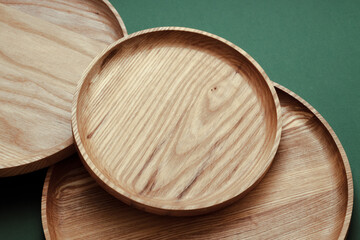 Wooden flat plates on a green background. The concept of ecological tableware. Products for modern kitchen. Zero emissions.