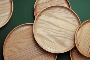 Wooden flat plates on a green background. The concept of ecological tableware. Products for modern kitchen. Zero emissions.