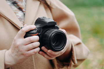 dslr camera in hands, young adult caucasian photographer woman in beige coat outdoors in autumn day, interesting hobby, amateur photography, creativity concept