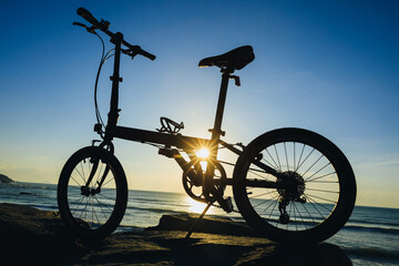 A folding bike on sunrise seaside rocka