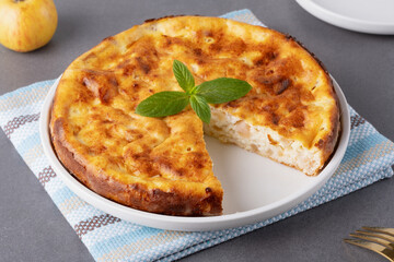 A delicious homemade cottage cheese casserole served on a textured table with fresh mint under bright kitchen lighting.