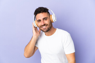 Caucasian man isolated on purple background listening music