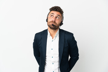 Telemarketer man working with a headset isolated on white background and looking up