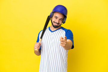 Young caucasian man playing baseball isolated on yellow background pointing front with happy expression