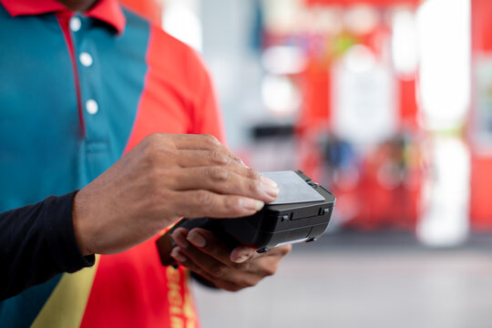 Hand of cashier hold credit card reader with blurry gas station background. Credit card payment. Buy and sell products & service. The concept of payment in gas station.