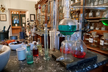 Chemistry flasks with liquids, herbs of medicinal plants in an old pharmacy