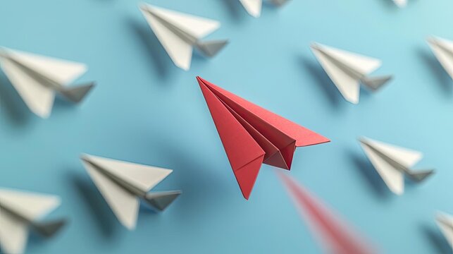 A bold red paper airplane leading a group of white paper airplanes, showcasing creativity and innovation. Set against a vibrant blue background.