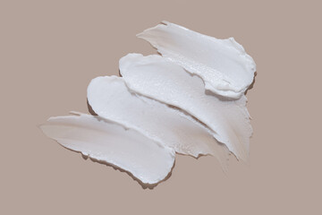 White cosmetic cream lotion swatch smear smudge on brown color background