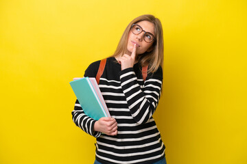 Young student woman isolated on yellow background background having doubts while looking up