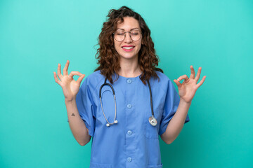 Young nurse caucasian woman isolated on blue background in zen pose