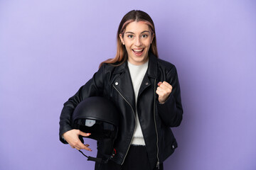 Young caucasian woman holding a motorcycle helmet isolated on purple background celebrating a victory in winner position