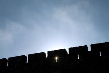A section of the ancient stone ramparts and walls of the Old City of Jerusalem, in silhouette with...