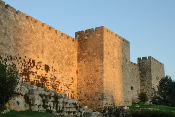 Fototapeta premium A section of the stone ramparts and walls of the Old City of Jerusalem, bathed in golden light at twilight in Israel.