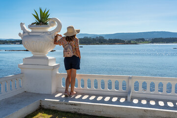 Tourist woman enjoying the sea views on the promenade of the island of La Toja, Galicia.