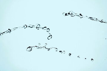 Water splash isolated on blue background. Transparent realistic water with movement and drops. Dynamic flight of water drops.