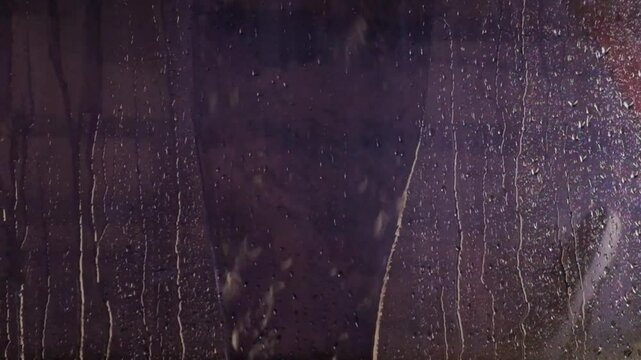 Abstract shapes, patterns and textures of raindrops and droplets on black glass background.. It looks calm and peaceful. 4K, 60Fps footage can be used for slow motion