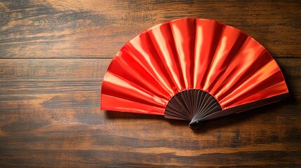 Red folding fan on a textured wooden surface