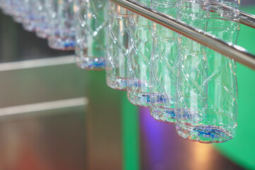 The empty drinking water bottles  hanging on the overhead conveyor belt for filling process.