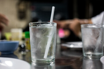 A glass of water with ice cubes and straw