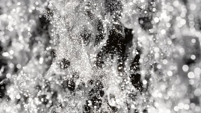 Slow-motion silver glitter backdrop with silver particles drifting gracefully against a dark background