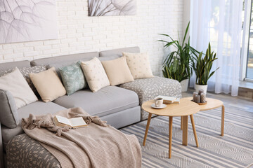 Light living room interior. Comfortable sofa near white brick wall indoors