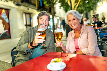 Senior couple toasting at camera enjoying evening in the city