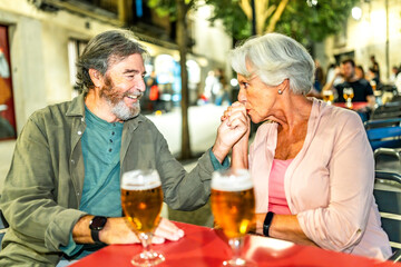 Senior woman kissing the hand of her husband at bar