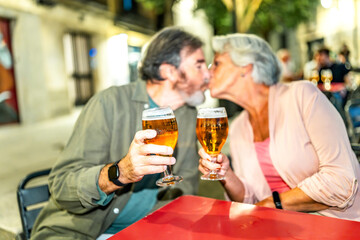 Senior couple kissing while toasting in an outdoor terrace