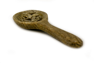 Sunflower seeds on a small wooden spoon isolated against a white background