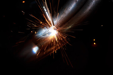 Arc welding. Welding pipes in inert gases. MIG / MAG. A bright flash of light and a sheaf of sparks.