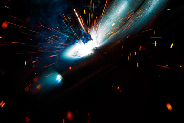 Arc welding. Welding pipes in inert gases. MIG / MAG. A bright flash of light and a sheaf of sparks.