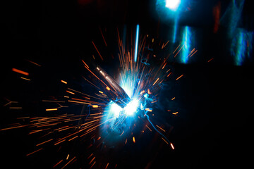Arc welding. Welding pipes in inert gases. MIG / MAG. A bright flash of light and a sheaf of sparks.