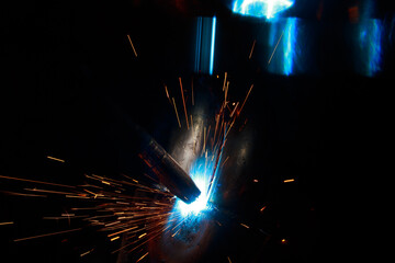 Arc welding. Welding pipes in inert gases. MIG / MAG. A bright flash of light and a sheaf of sparks.