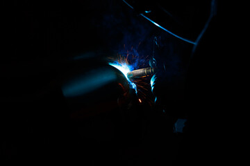 Arc welding. Welding pipes in inert gases. MIG / MAG. A bright flash of light and a sheaf of sparks.