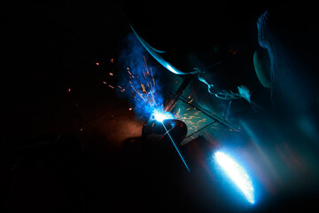 Arc welding. Welding pipes in inert gases. MIG / MAG. A bright flash of light and a sheaf of sparks.