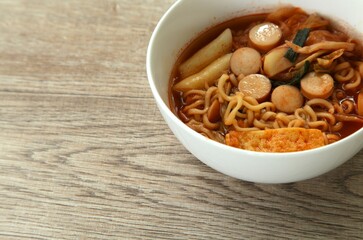 Korean yellow noodles topping slice sausage and cabbage with tofu coupple  tokpokki in kimchi soup in bowl