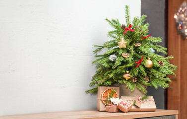 small christmas tree with gifts stands on table in home interior