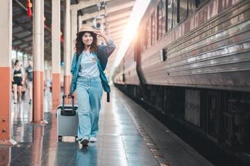 Woman with suitcase on train platform, dressed casually, enjoying travel and adventure at sunrise.