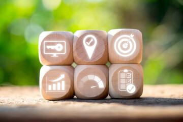 Wooden blocks with icons symbolizing objectives and key results, illustrating business strategy and goal setting.