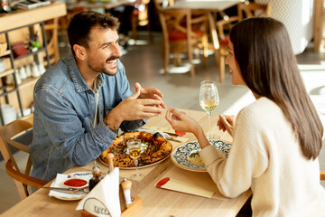 A joyful couple enjoying a delightful meal together at a cozy restaurant during a sunny afternoon