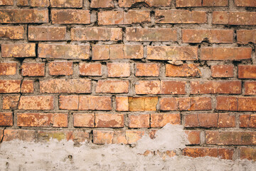 Old grungy brick wall. Free space for an inscription. Can be used as a background or poster. Fragment of a wall with bumps and shabby plaster.