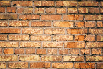 Old grungy brick wall. Free space for an inscription. Can be used as a background or poster. Fragment of a wall with bumps and shabby plaster.