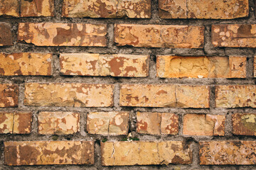 Old grungy brick wall. Free space for an inscription. Can be used as a background or poster. Fragment of a wall with bumps and shabby plaster.